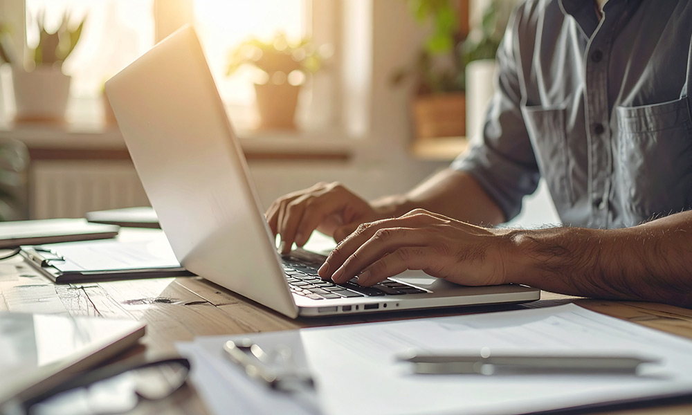 Person arbeitet am Laptop und prüft Unterlagen zur Auftragsplanung. Hausmeisterservice Köln
